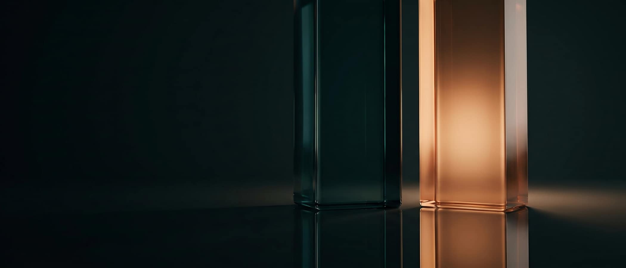 Two tall glass monoliths side by side, one dark teal and one glowing amber