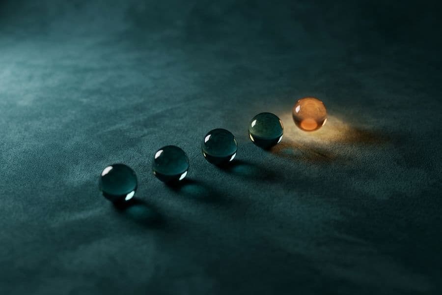 Five glass spheres on teal suede, the last one glowing amber